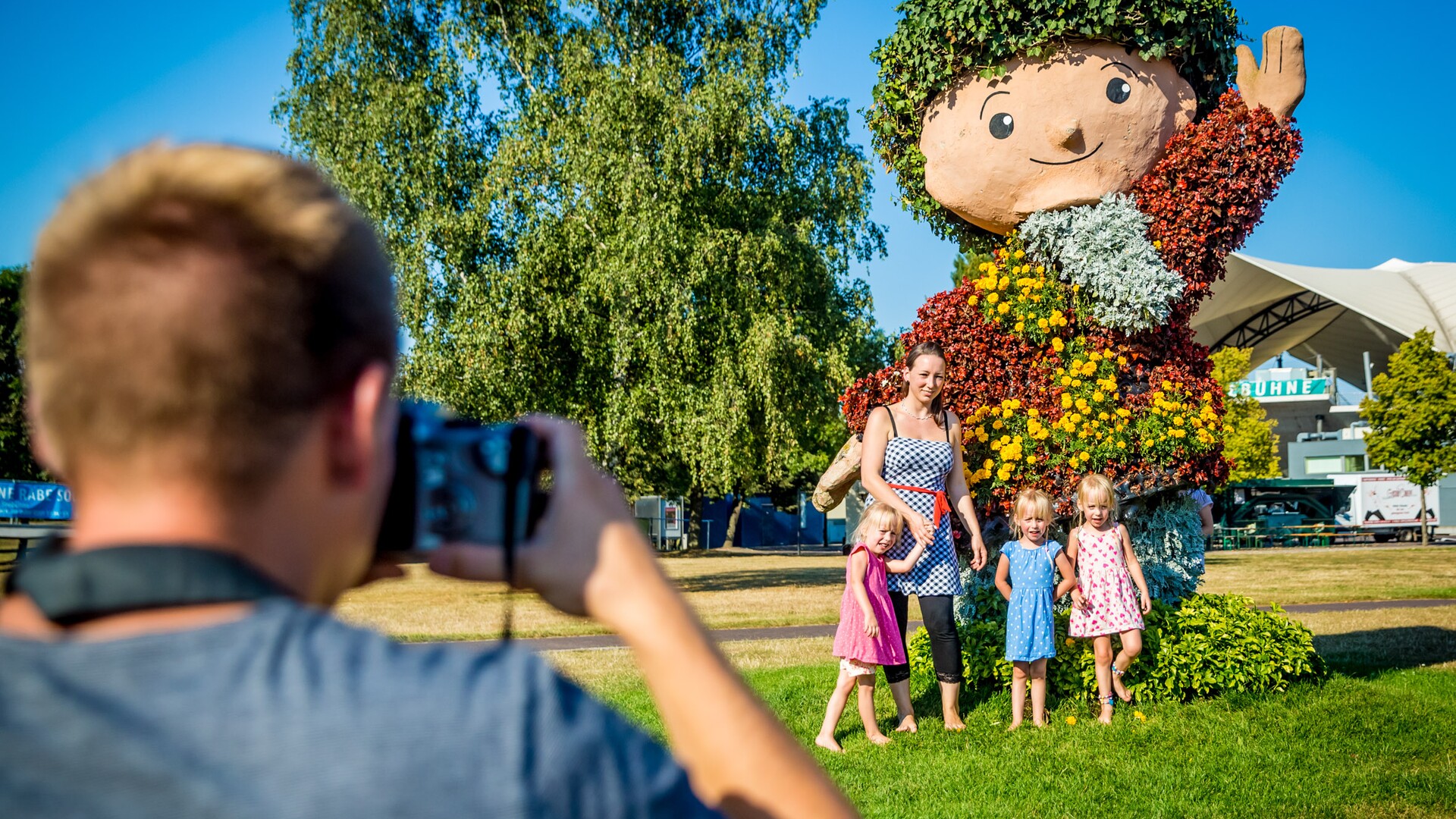 Vater fotografiert seine Frau und Töchter vor dem Sandmann im Elbauenpark Magdeburg