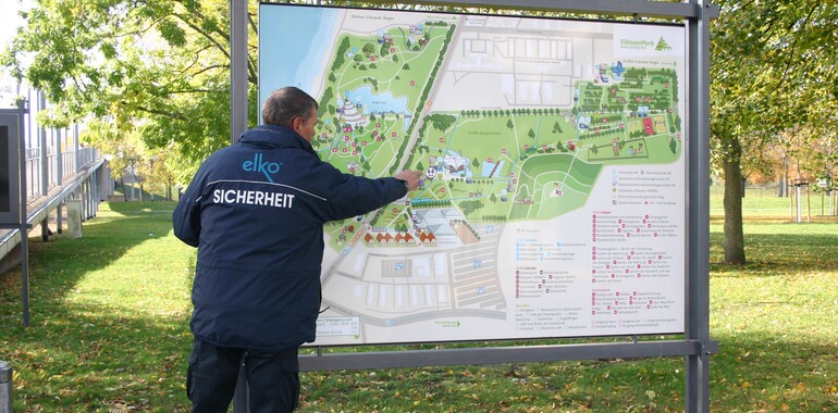 Der Wachmann zeigt den Weg auf dem Geländeplan. Hier steht auch die Notfallrufnummer drauf.