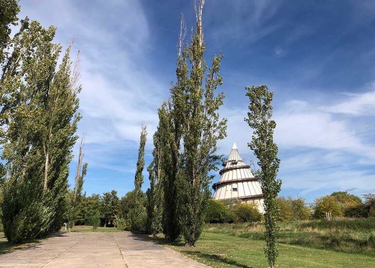 Platz umgeben von Säulenpappeln. Im Hintergrund sieht man den Jahrtausendturm.