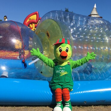 Das Maskottchen der Wohnungsbaugesellschaft Magdeburg vor den Hüpfburgen inmitten des Elbauenparks.